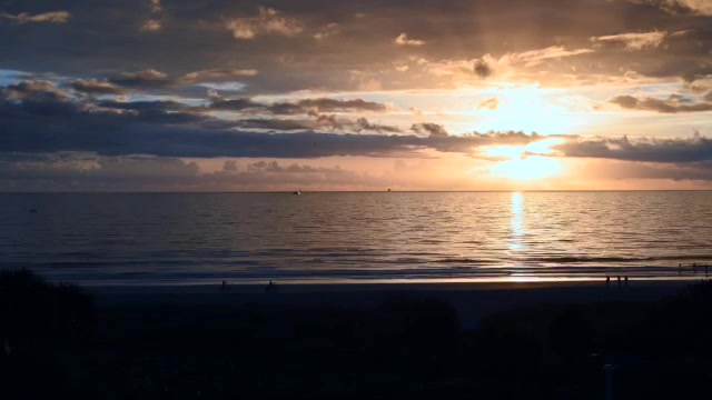 Serene Beach Sunset with Solitary Walker Along the Horizon